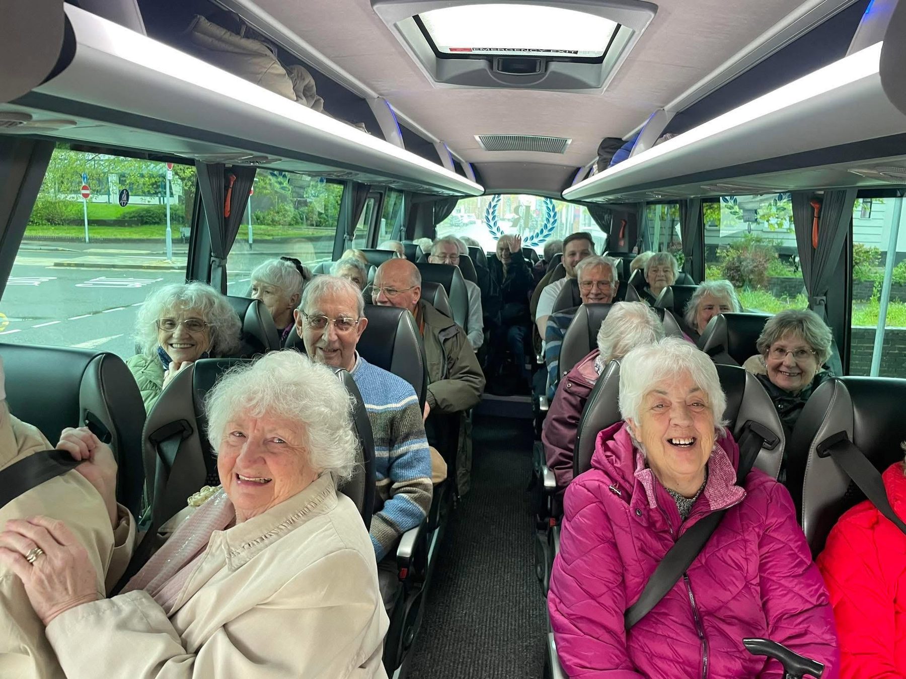 A smiling group of passengers on board a Robb's coach