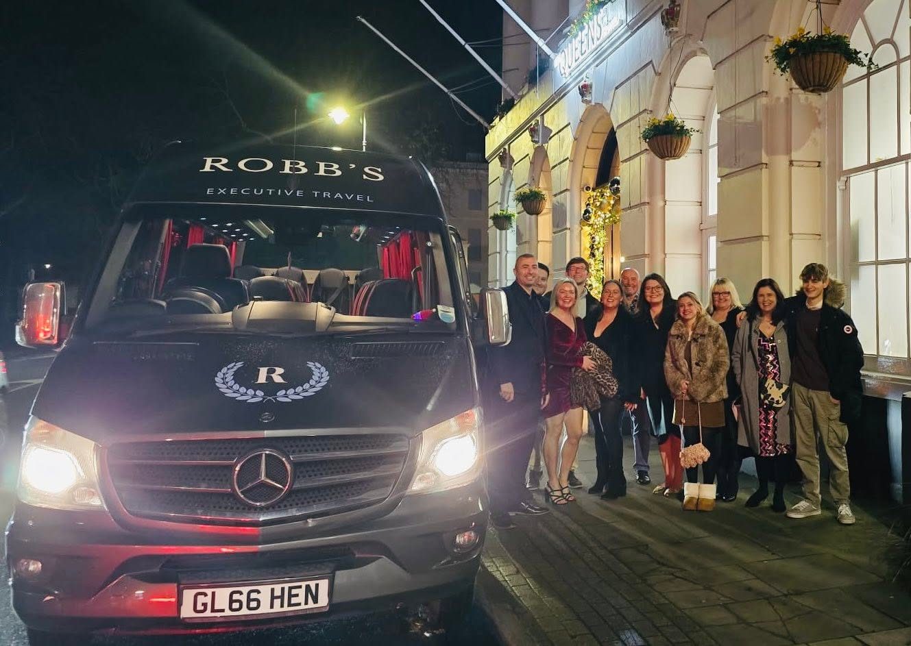 A group posing outside a Robb's minibus at night after a night out