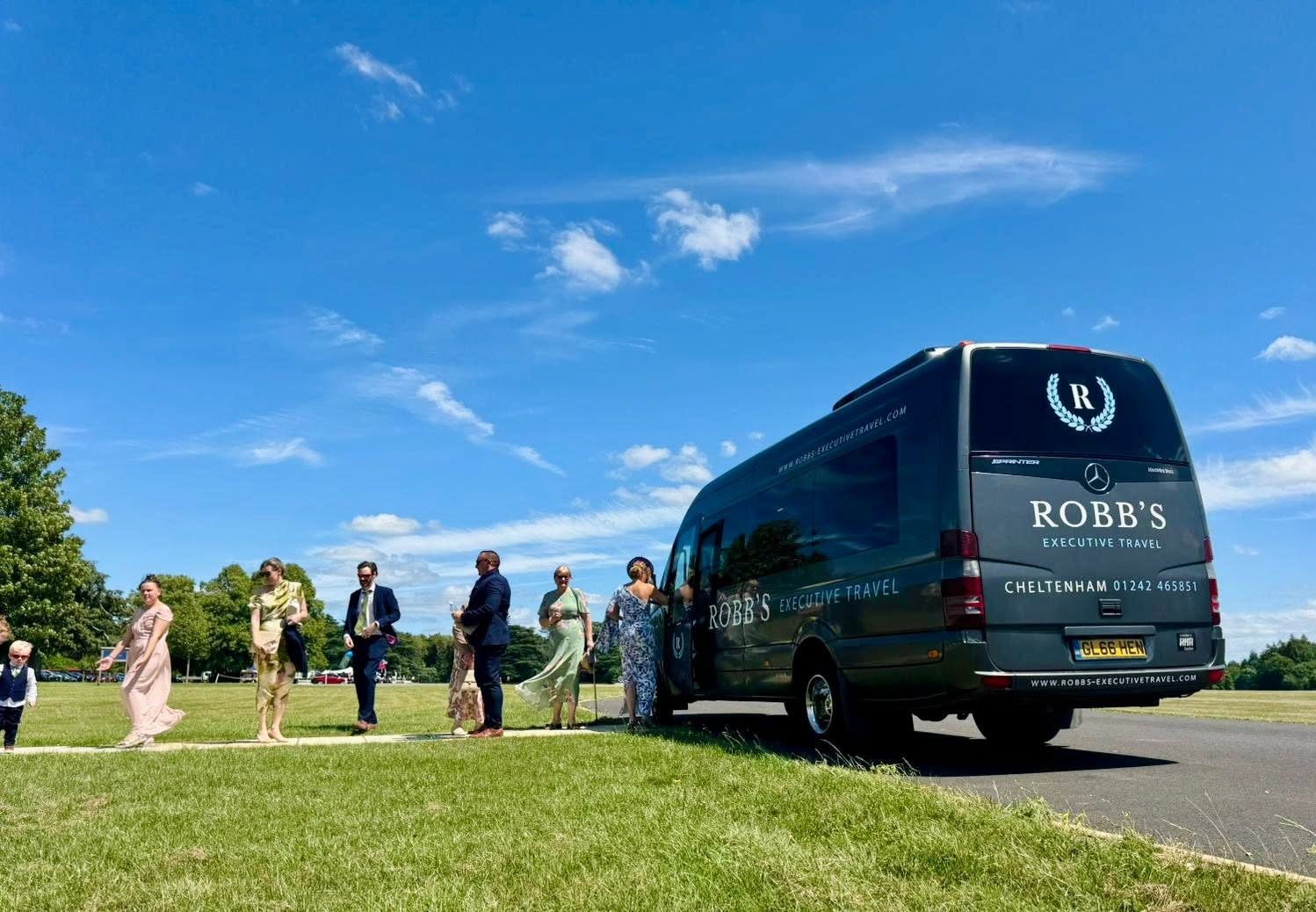 Wedding guests crossing the lawn towards a Robb's minibus